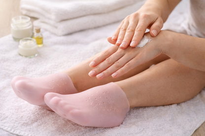 Femme appliquant une crème hydratante et portant des chaussettes en silicone p